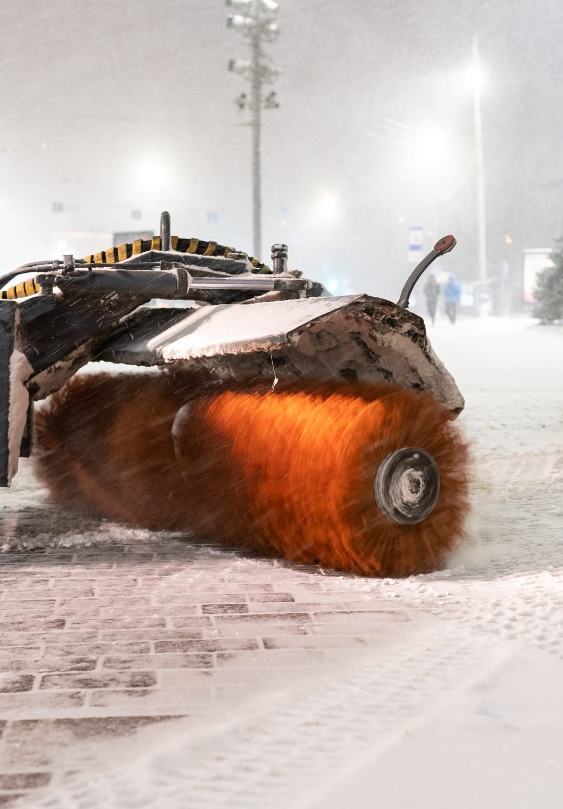 Vehicles for clearing snow. Cropped shot of tractor with rotary broom cleaning sidewalk in winter city. Municipal services working in city after blizzard, clearing city streets after end of snowstorm